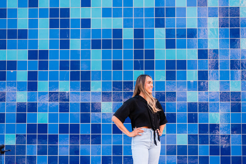 girl getting her senior photos taken at the blue tile wall in austin texas