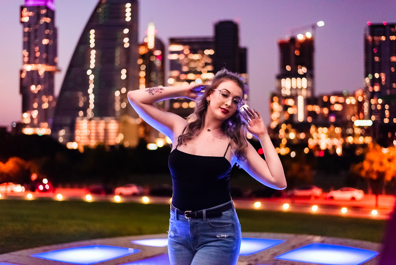 senior photographer in austin texas capturing a girl posing in front of the cityscape in downtown austin.