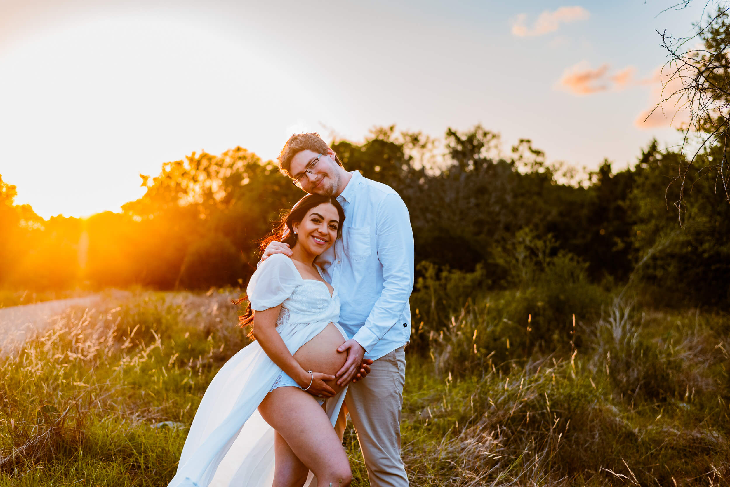 couple posing for maternity photoshoot at sunset