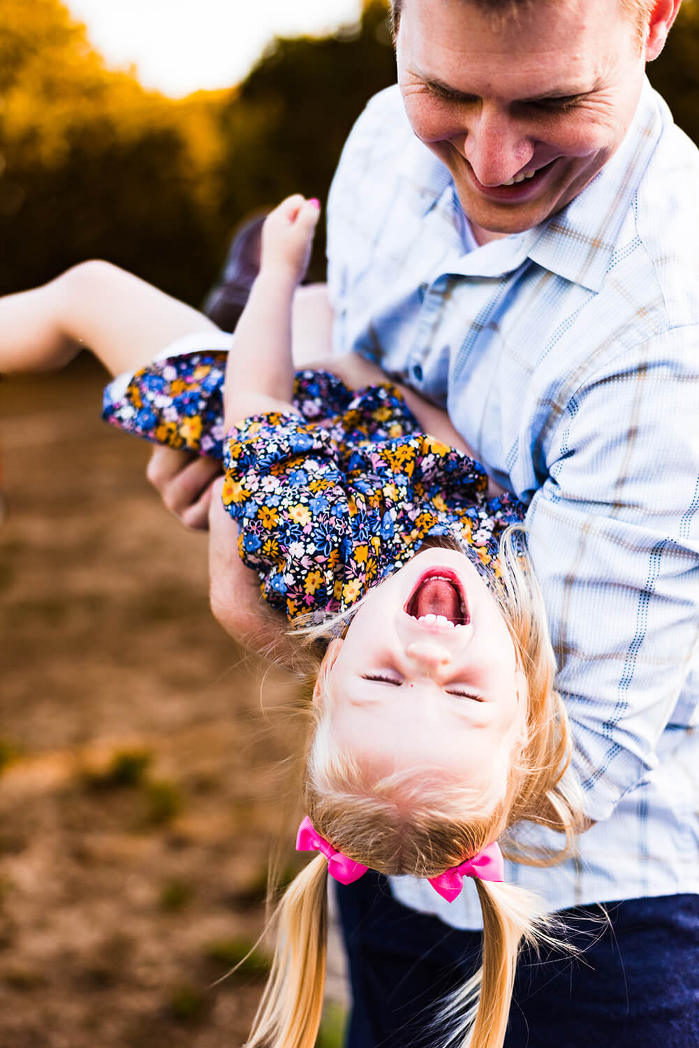 a little girl laughing while her dad plays with her during her family photoshoot in austin texas