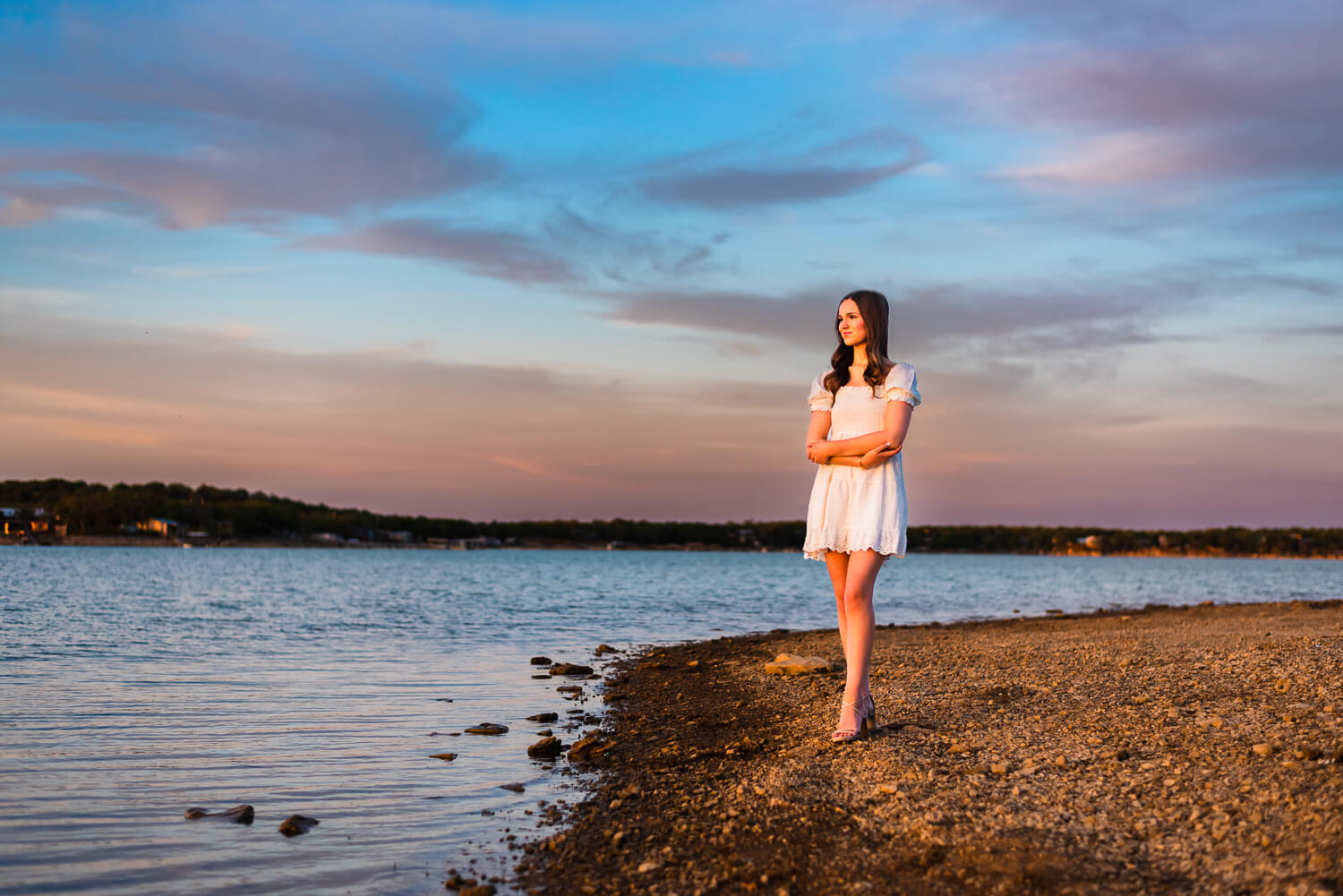girl standing at the shoreline of a lake in texas getting her senior photos taken