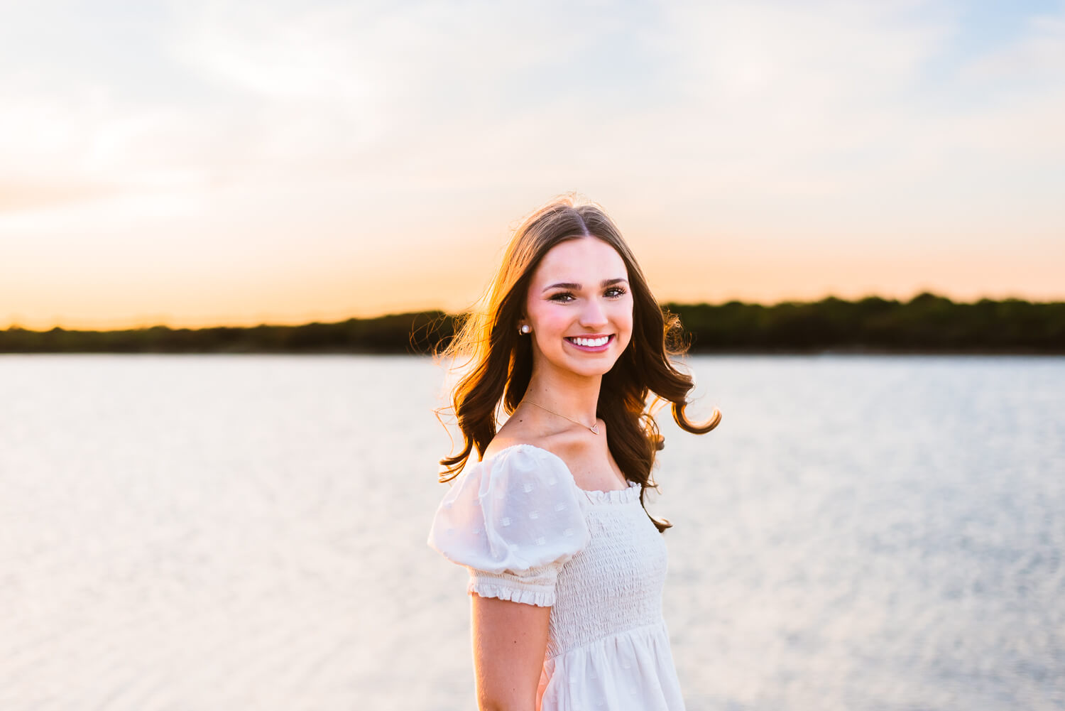 brunette senior girl smiling in her senior photos at lake cisco in texas.