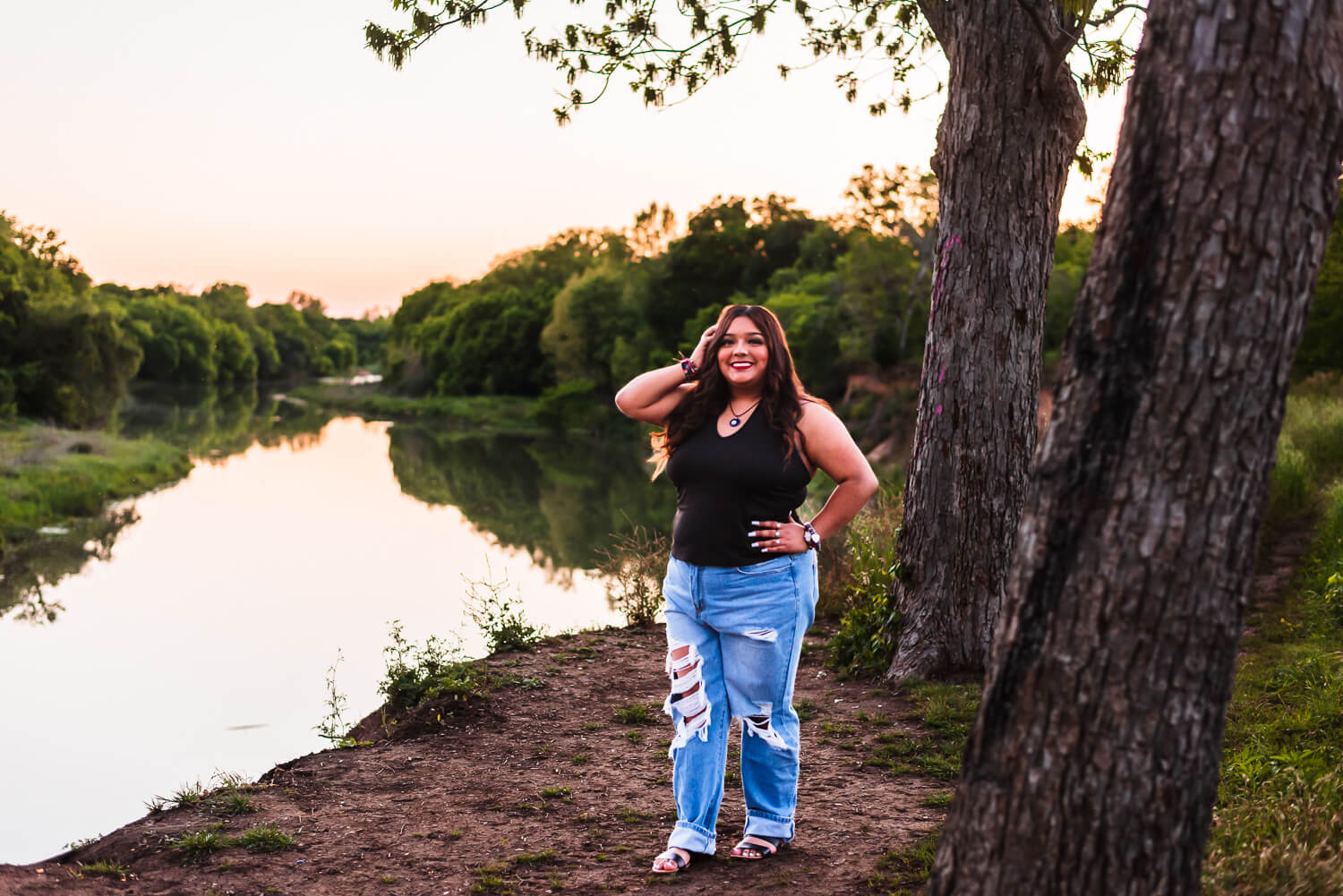 del valle high school senior girl posing for senior photos by the coloarado river in austin texas