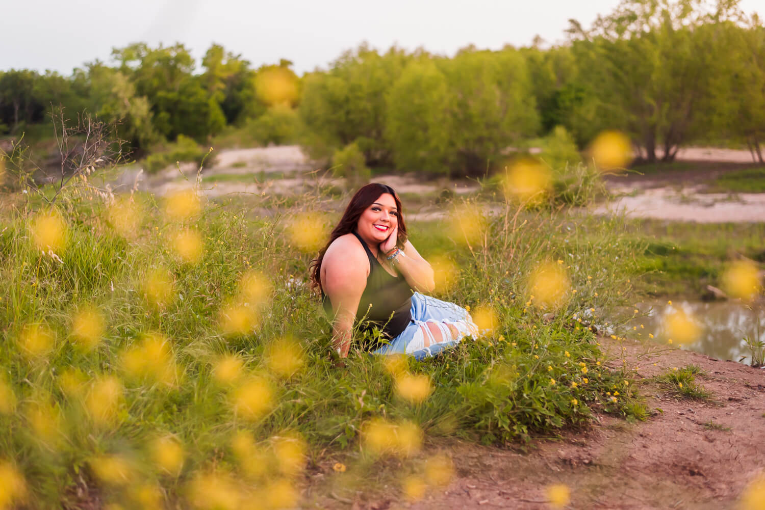 del valle high school senior sitting in yellow flowers for her high school senior photoshoot
