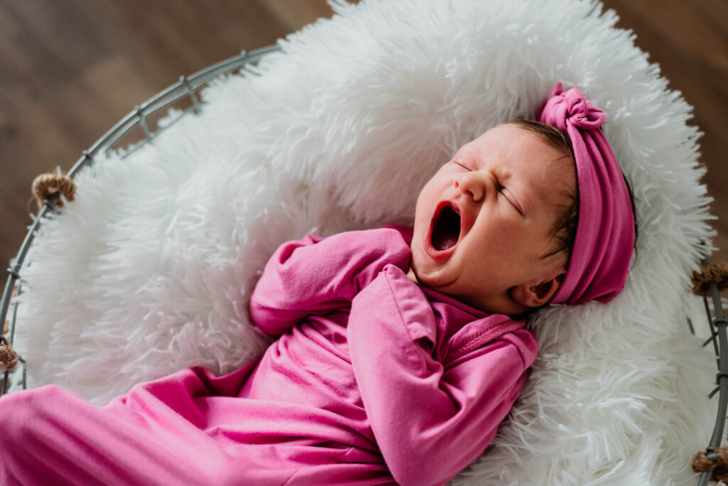 newborn baby girl yawning during her in home newborn photography session
