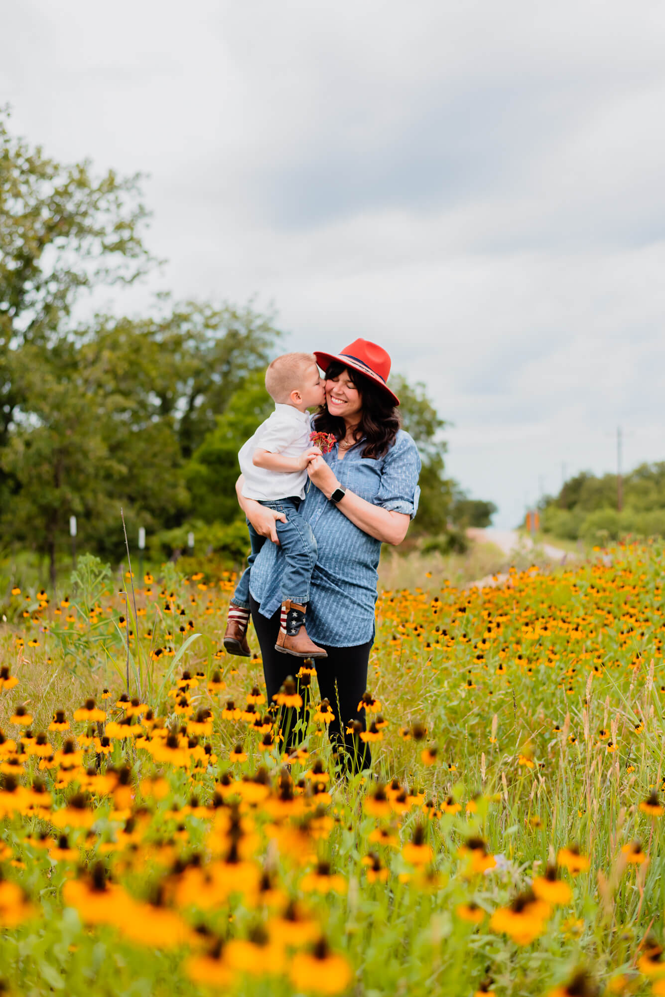 little boy kissing his mom in a field of flowers