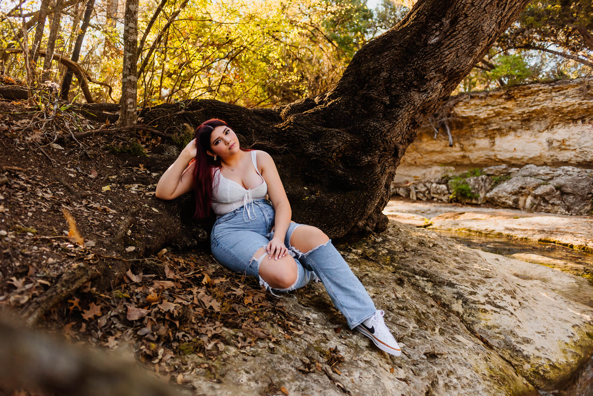 girl posing by large tree for senior photos in austin texas