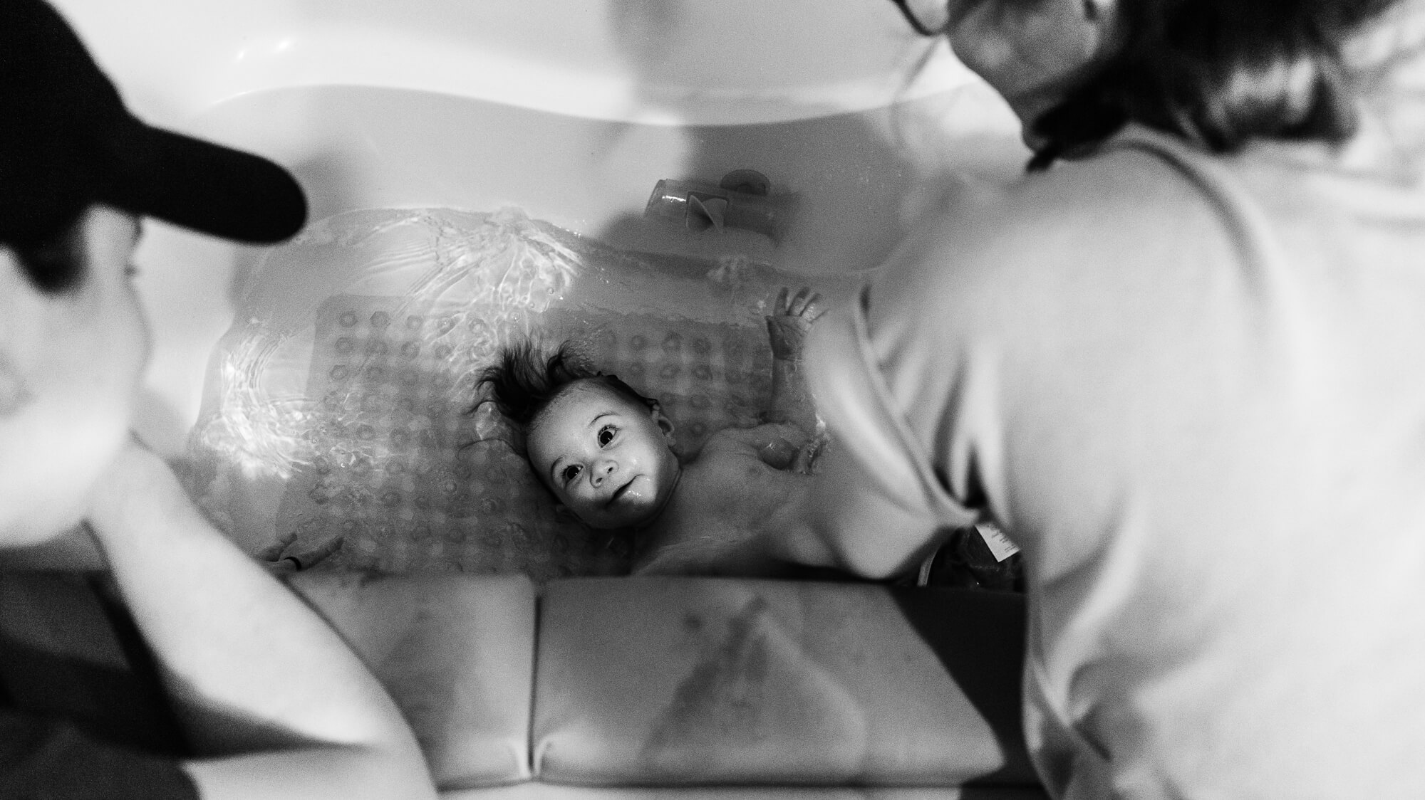 family bathing their 6 month old daughter in the bathtub
