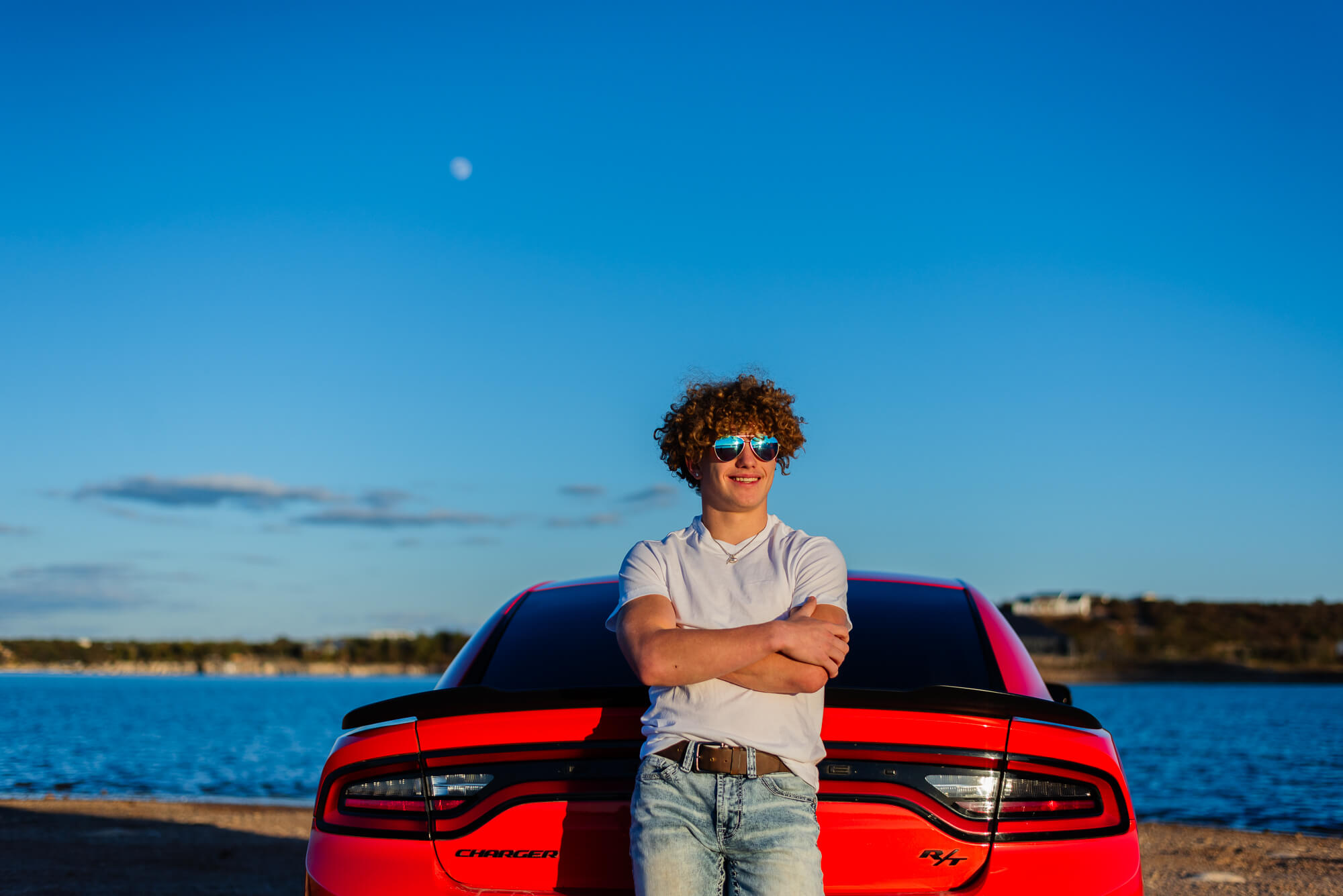 senior boy posing with red mustang for his senior pictures
