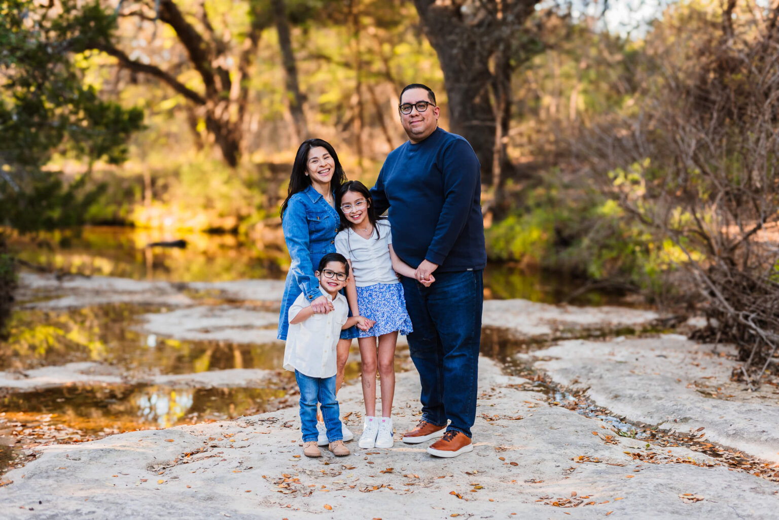 family of four smiling at the camera for a family portrait