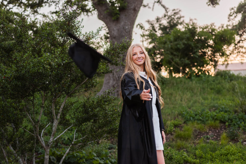 girl throwing graduation cap at camera during senior photoshoot in austin texas