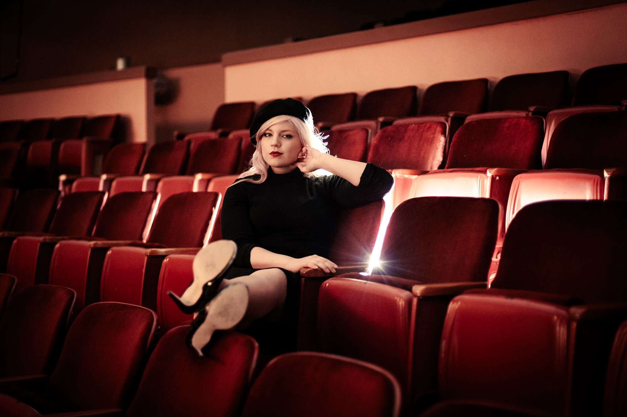 girl sitting in old movie theater seats for senior photoshoot