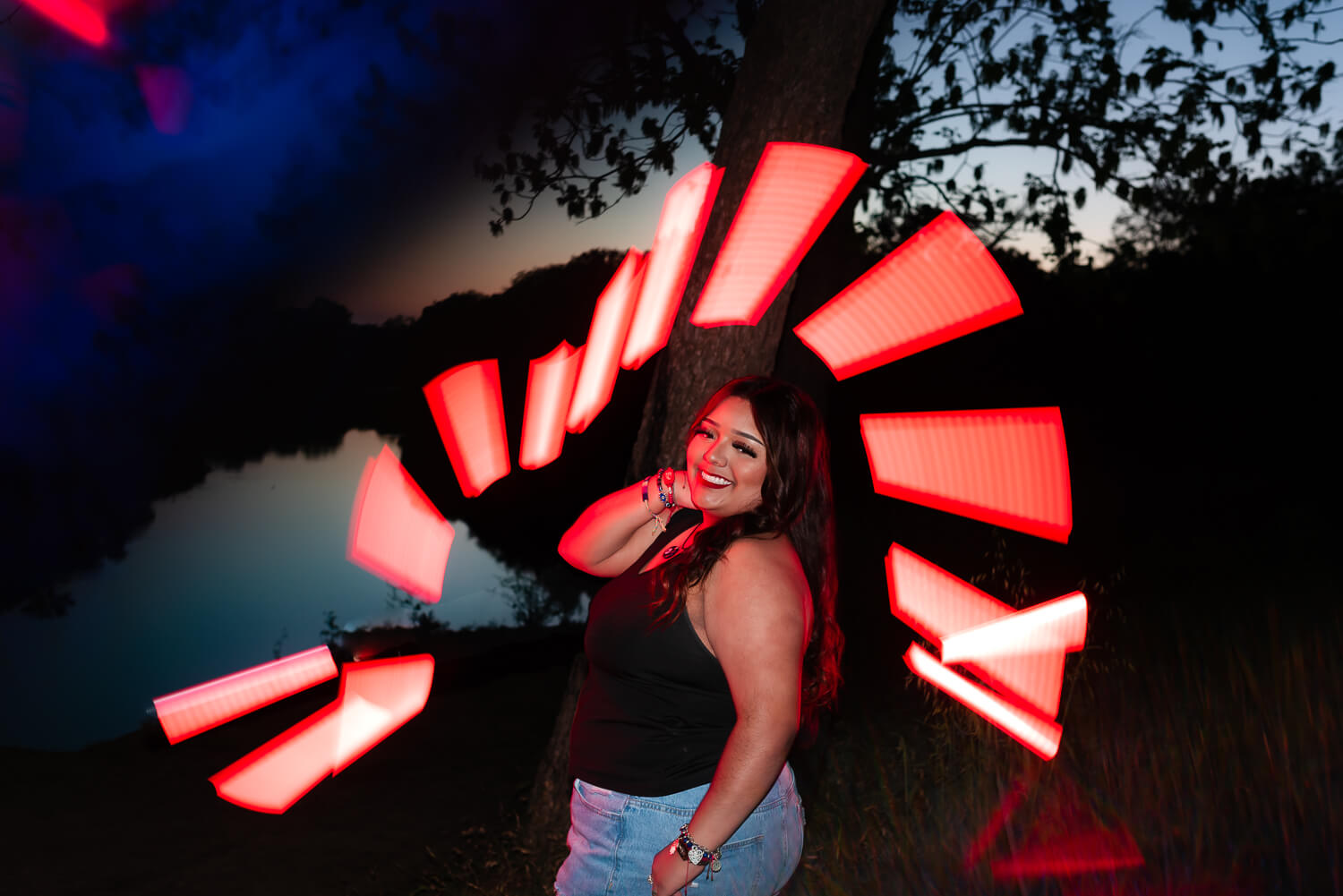 senior girl with bright red light painting portrait for a aries astrology sign