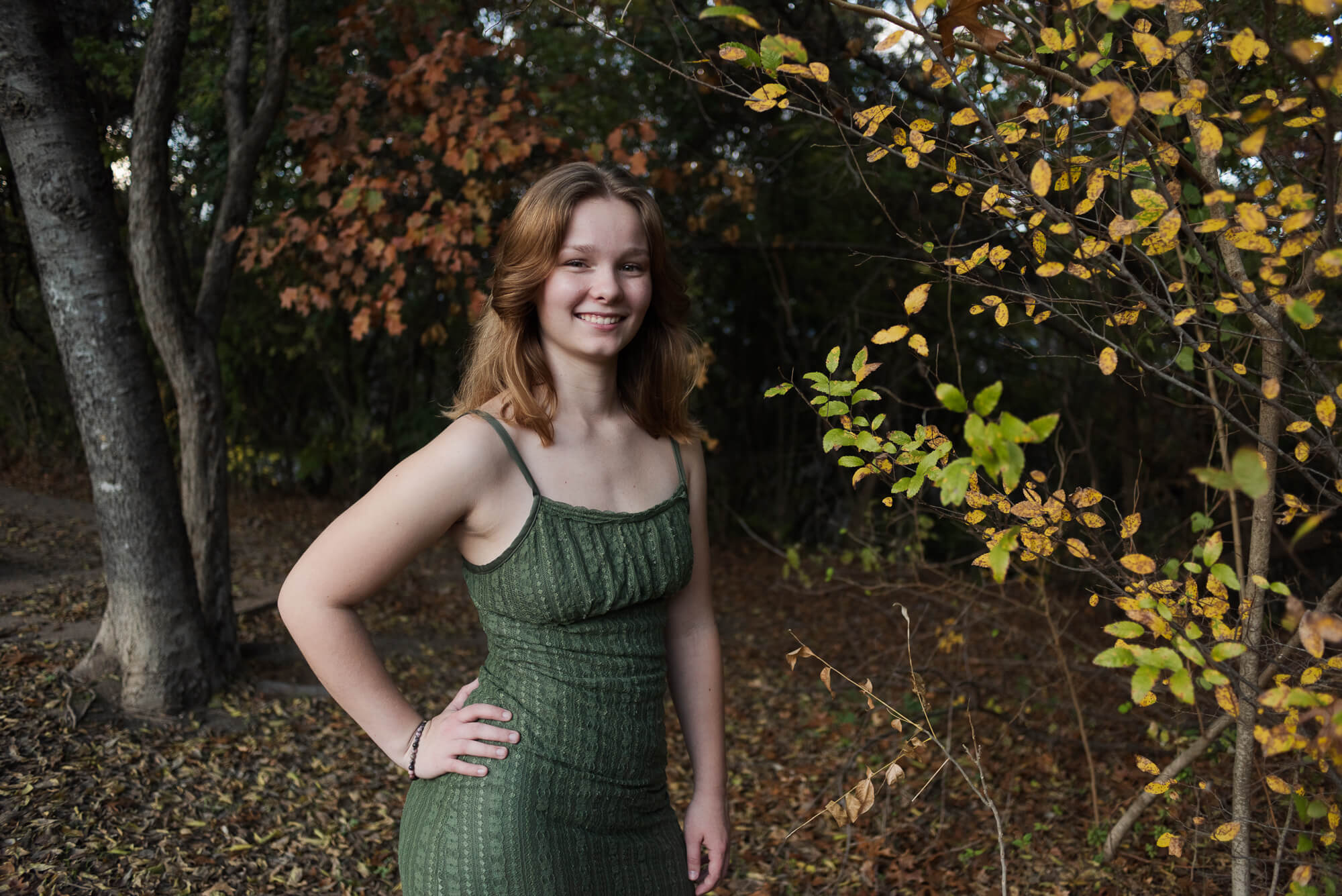 girl smiling by color fall foilage in texas for senior photos