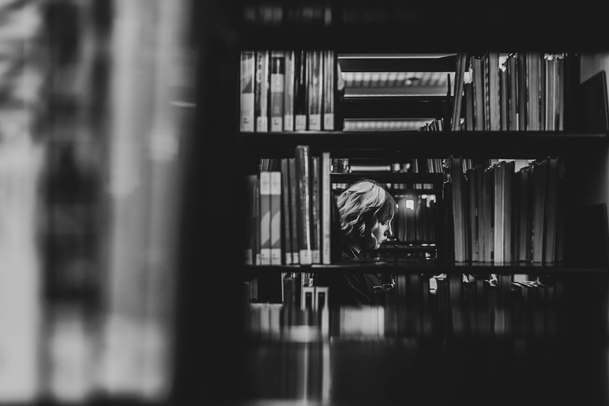 girl reading a book in the stacks at austin public library