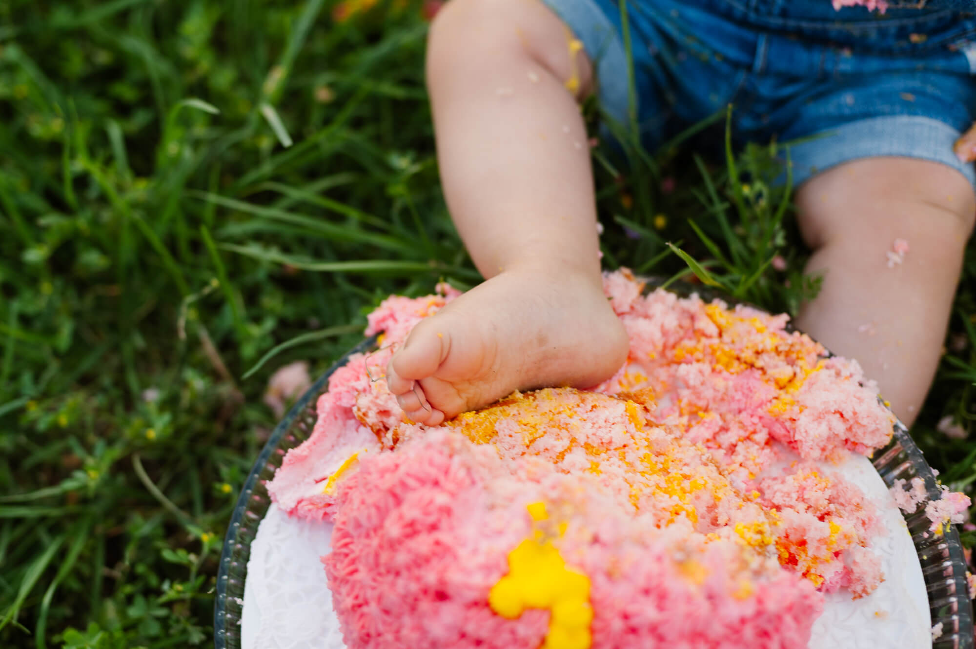 baby putting her foot into her birthday cake