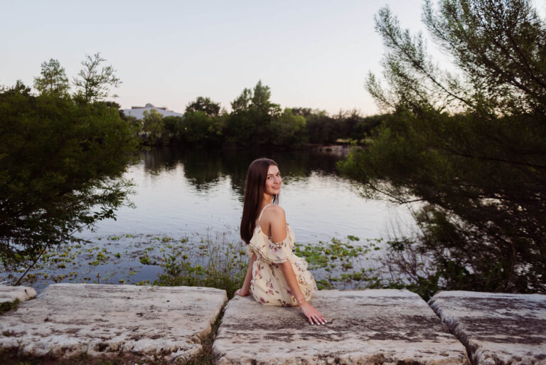 senior girl looking out at lady bird lake at shoal beach at sunset