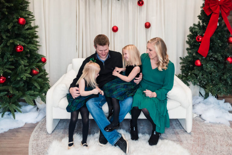 family sitting in studio decorated for a christmas photoshoot in austin texas