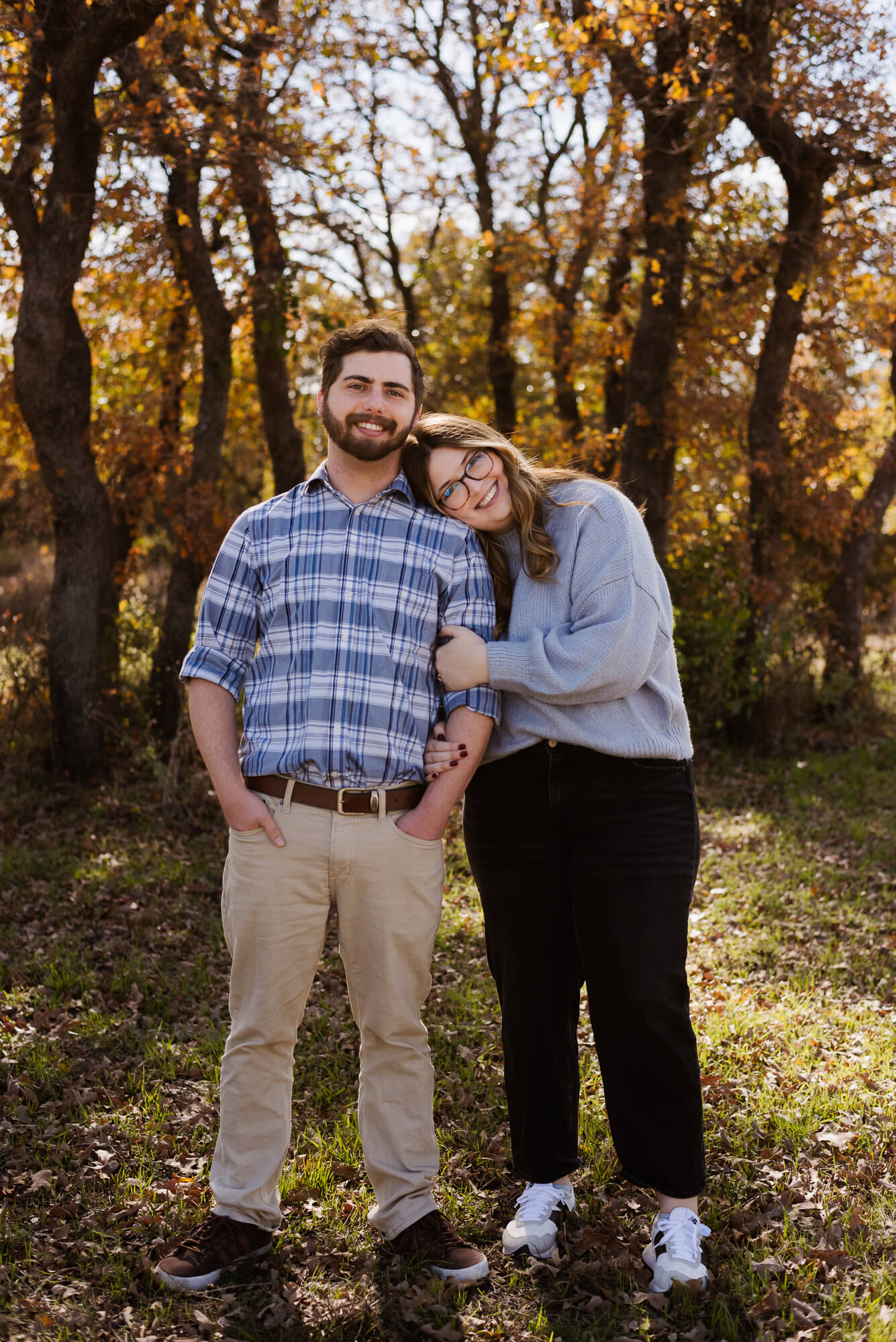 engagement photos during fall with girl leaning on boy shoulder and them swinging each other around