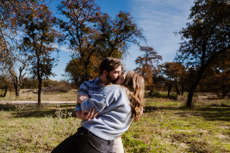 engaged couple kissing outside during fall engagement photoshoot