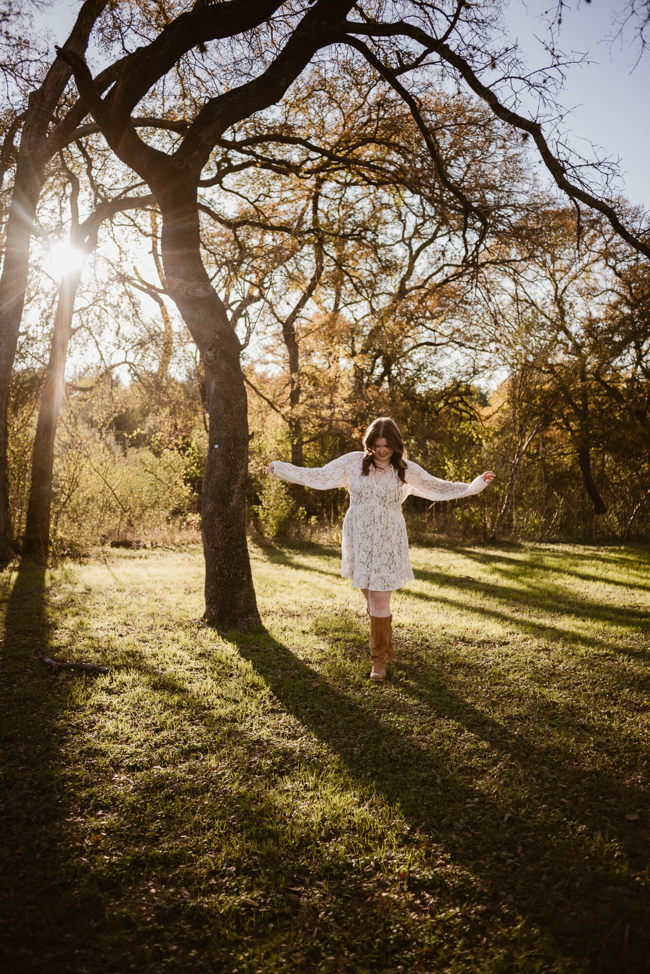 girl balancing walking during fall senior photoshoot with sun and fall colors in background
