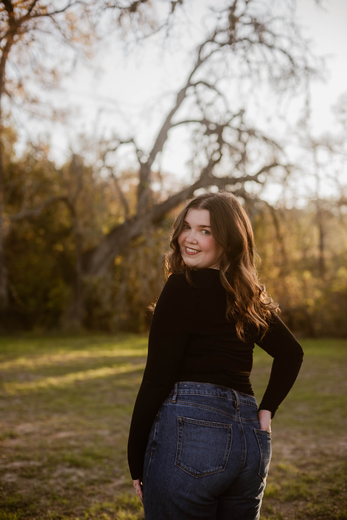 fall senior photo of girl looking over her shoulder at commons ford ranch in austin