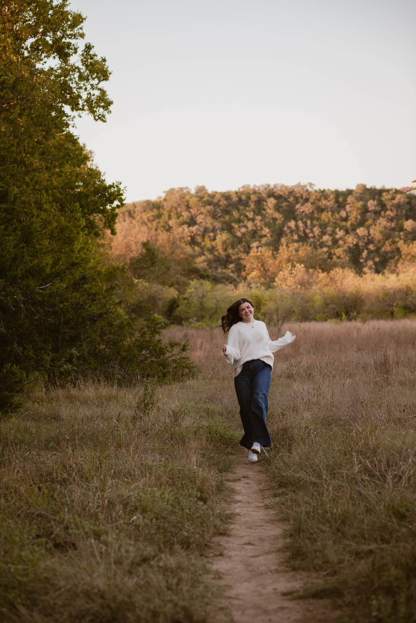 girl running to camera laughing during fall senior photoshoot