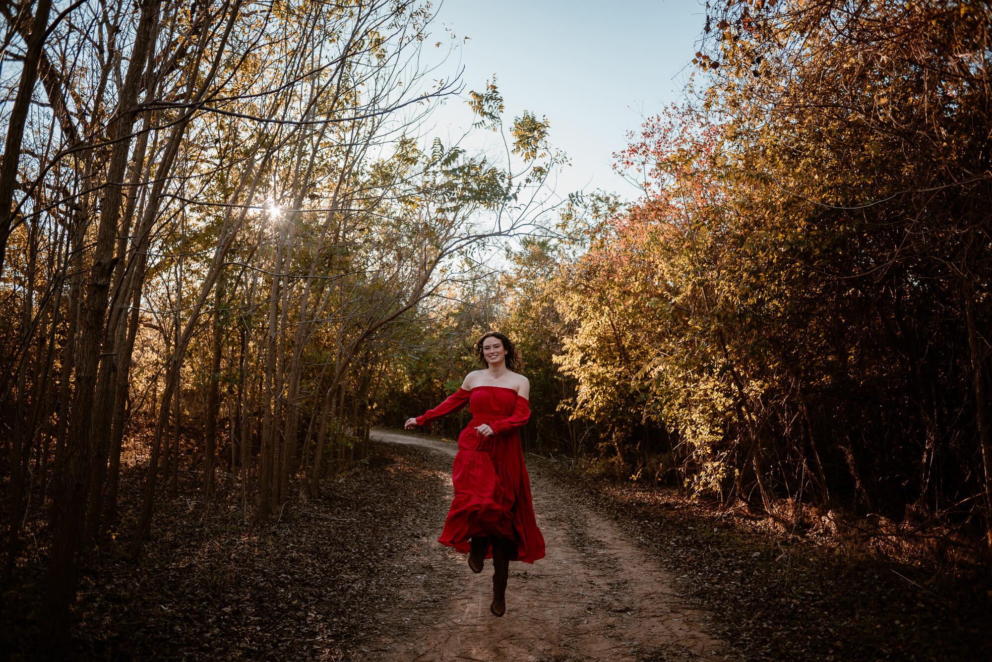 girl with red dress skipping during fall senior pictures at commons ford ranch
