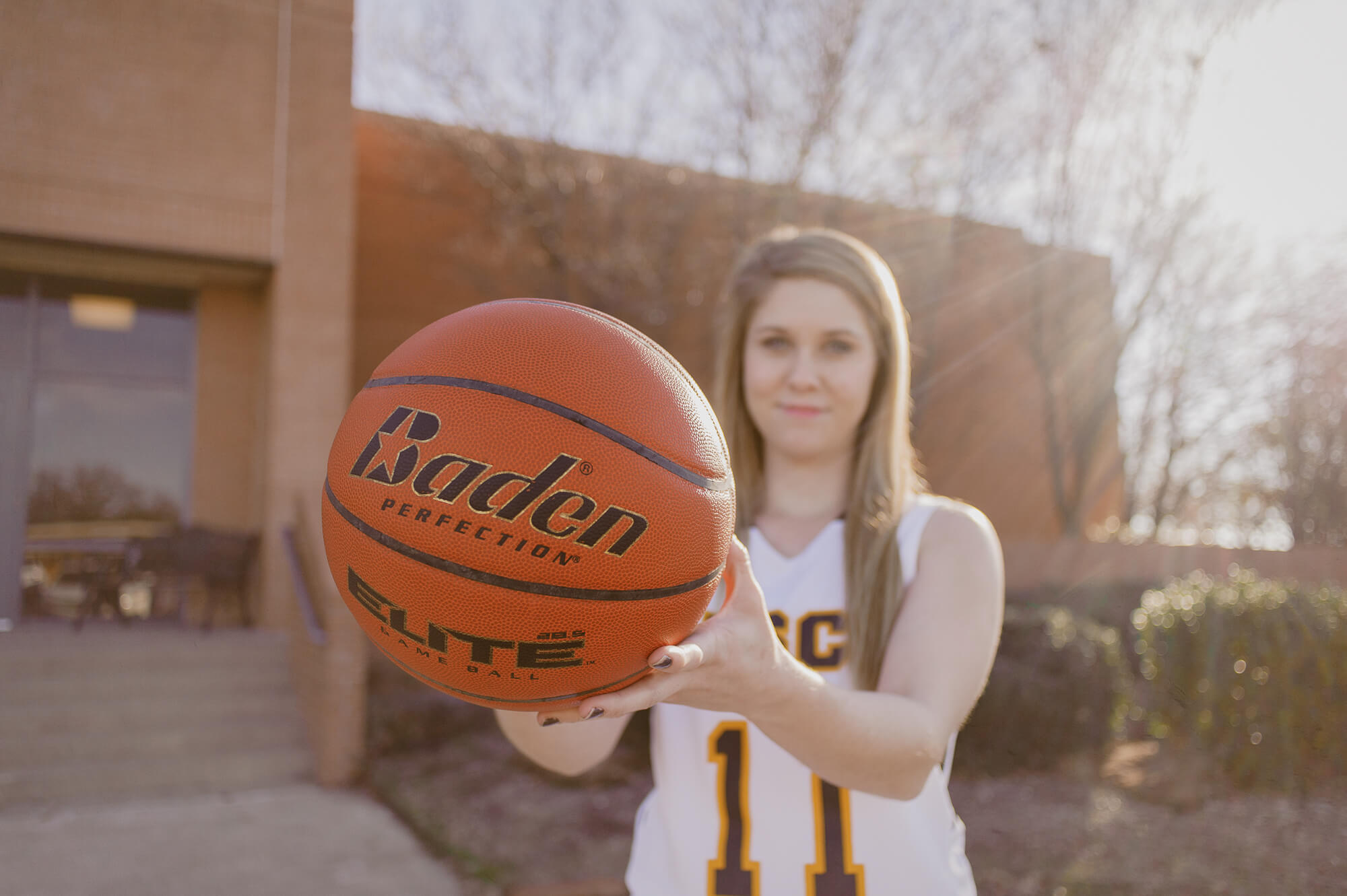 girl holding basketball in front of high school gym