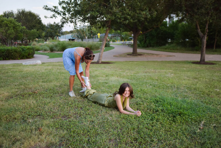 mom pulling sock off daughter during senior photoshoot