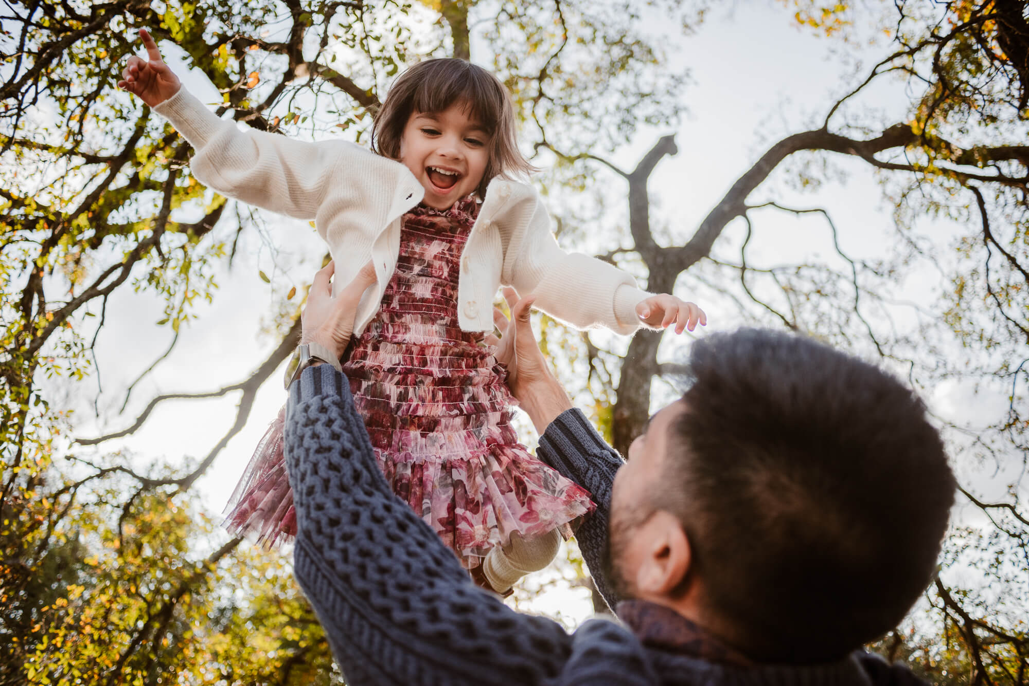 dad throwing up daughter during family photoshoot at circle c park and little girl is laughing and smiling