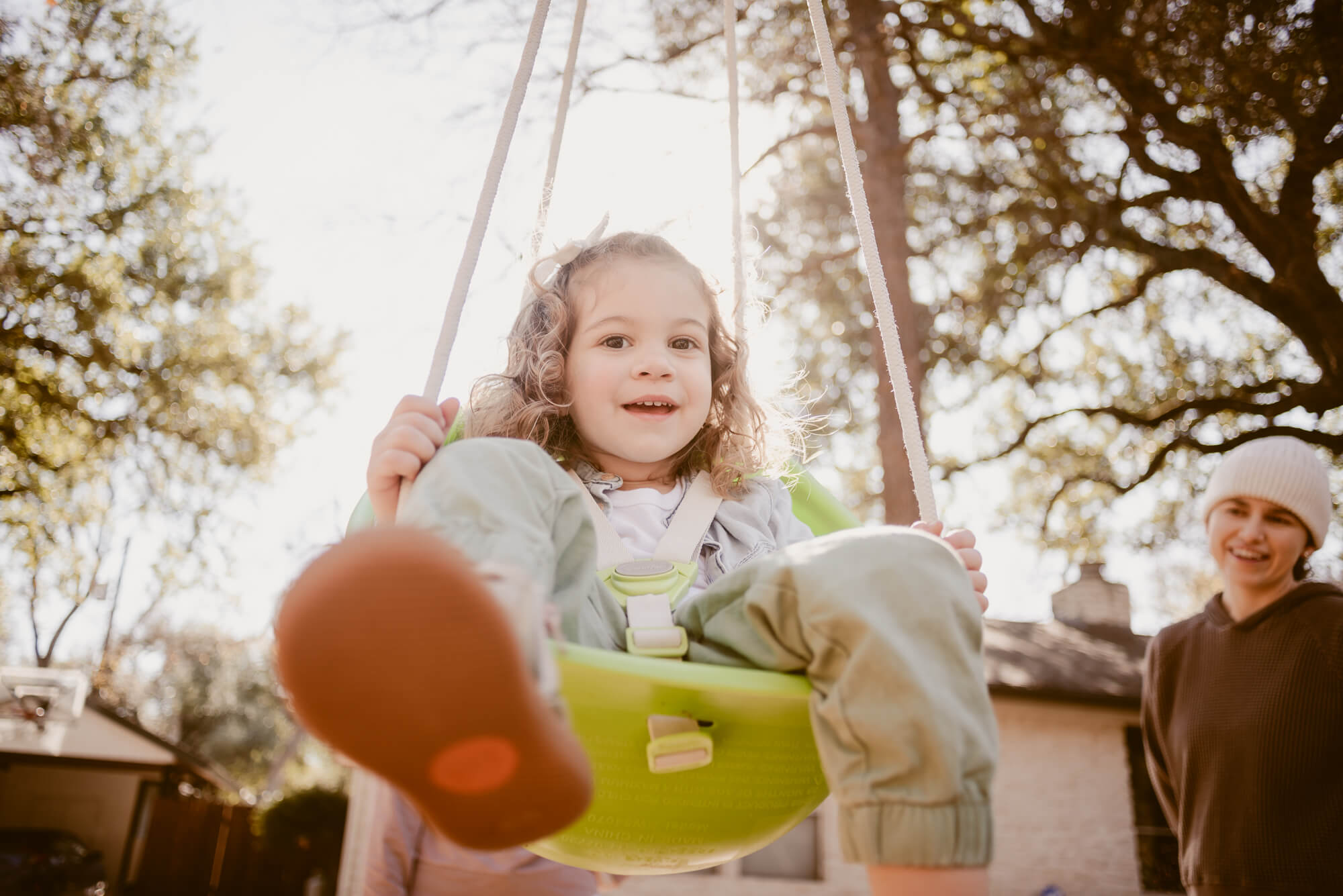 Toddler smiling on the swing at home during an at-home family photoshoot in Austin
