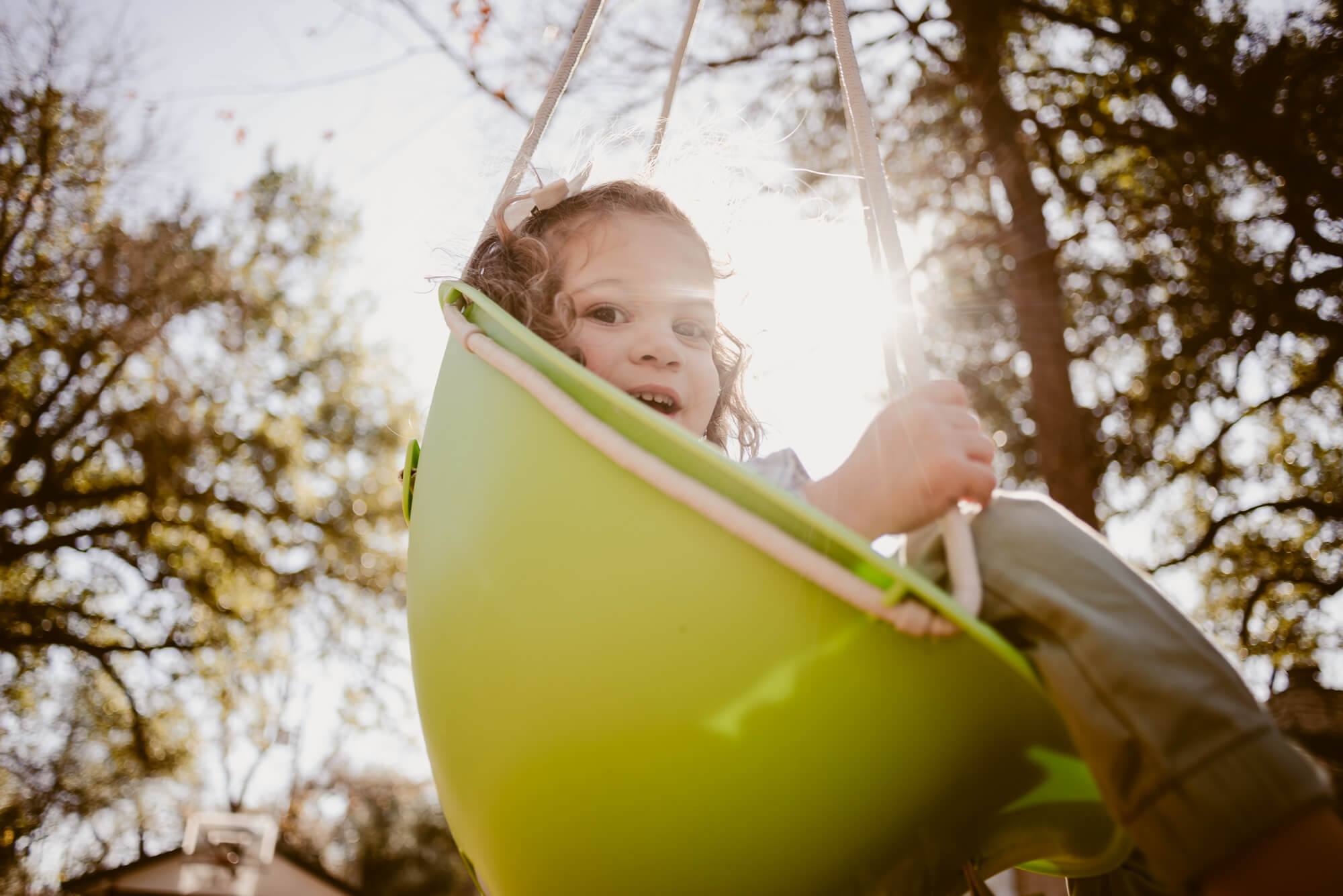 Toddler smiling on the swing at home during an at-home family photoshoot in Austin