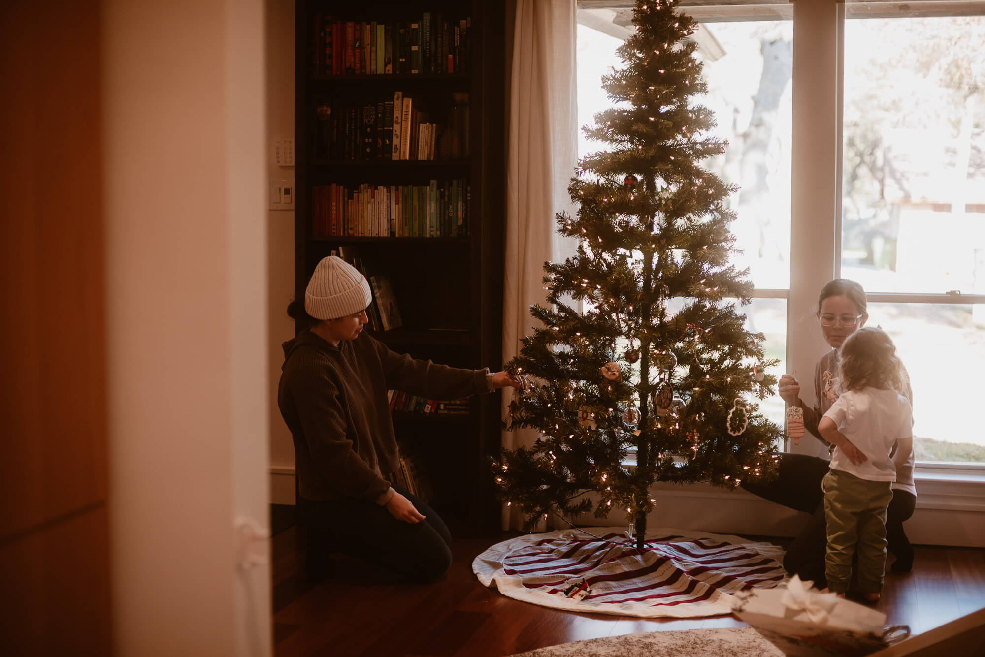 Family decorating their Christmas tree together during an in-home session in Austin
