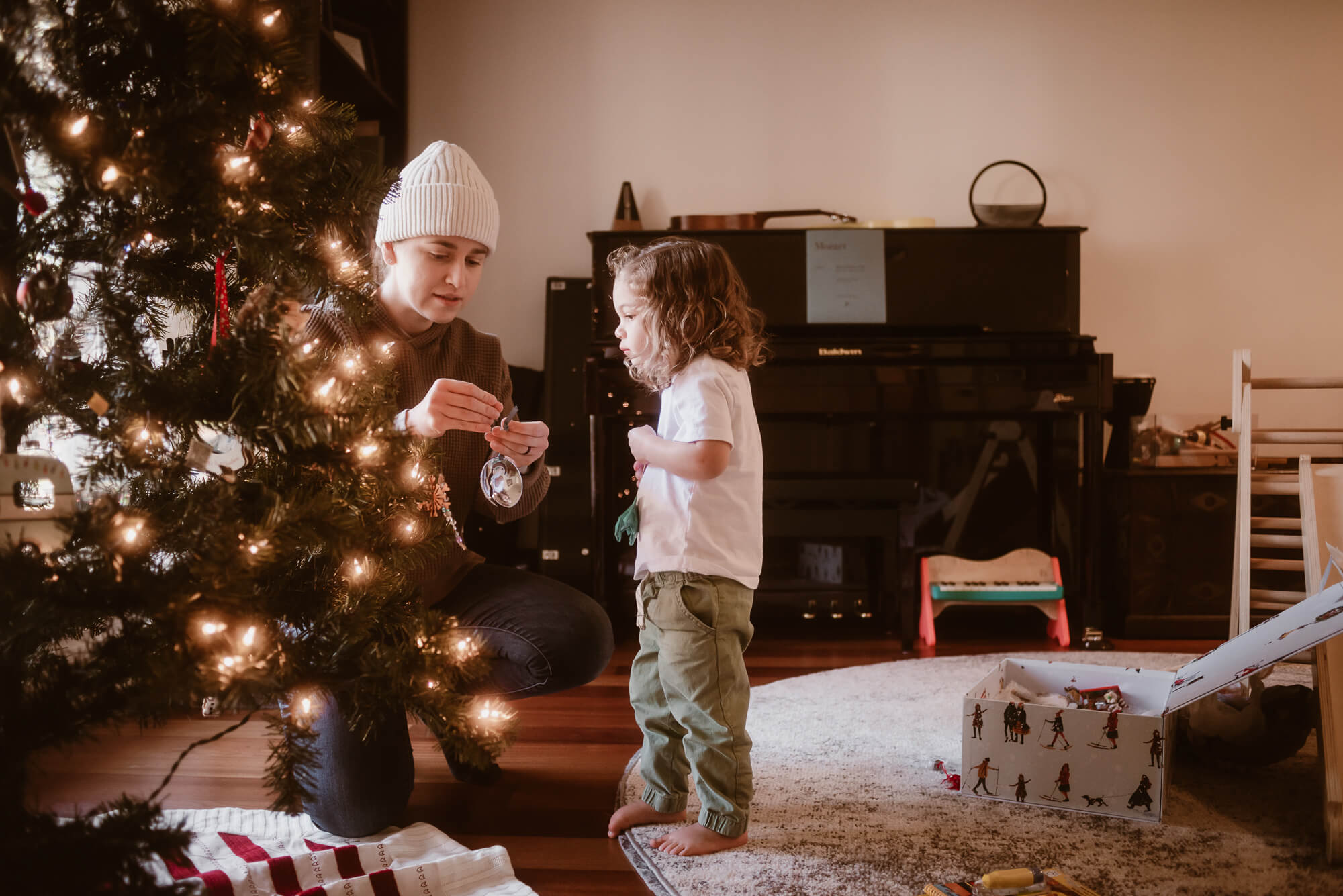 Toddler helping decorate the Christmas tree during an in-home family session
