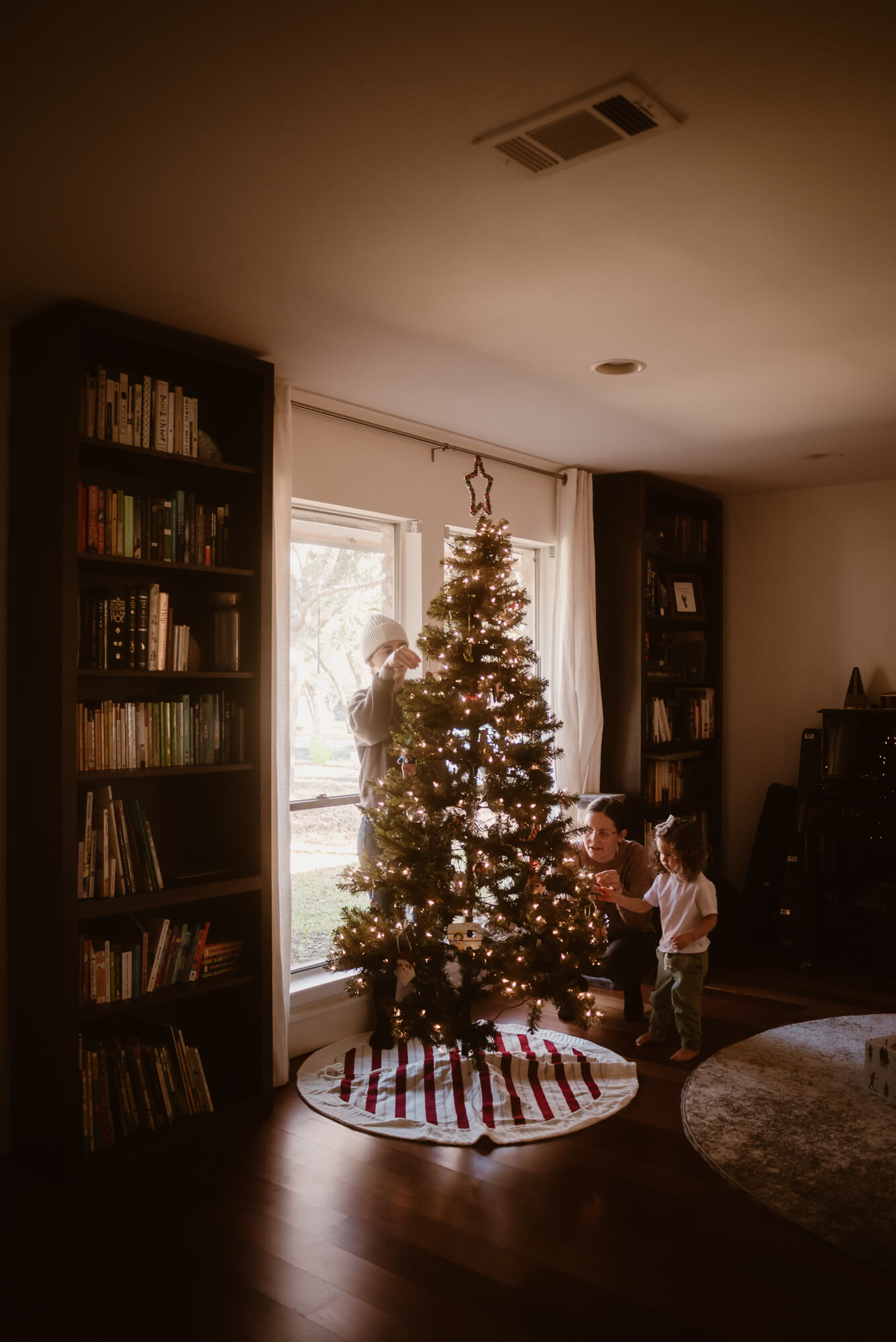 In-home Christmas family photography in Austin, family trimming the tree together