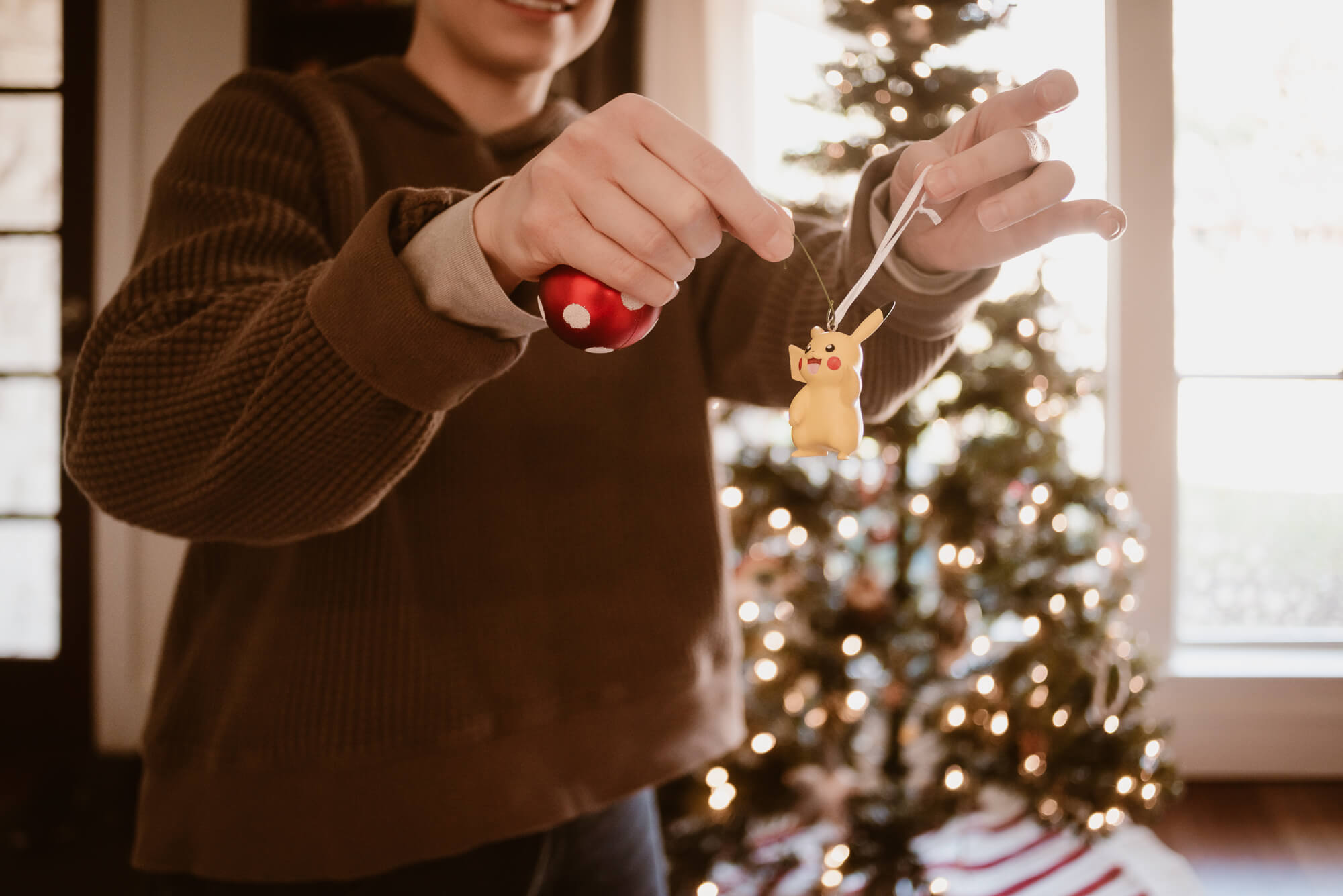 Close-up of hands hanging an ornament during Christmas tree decorating