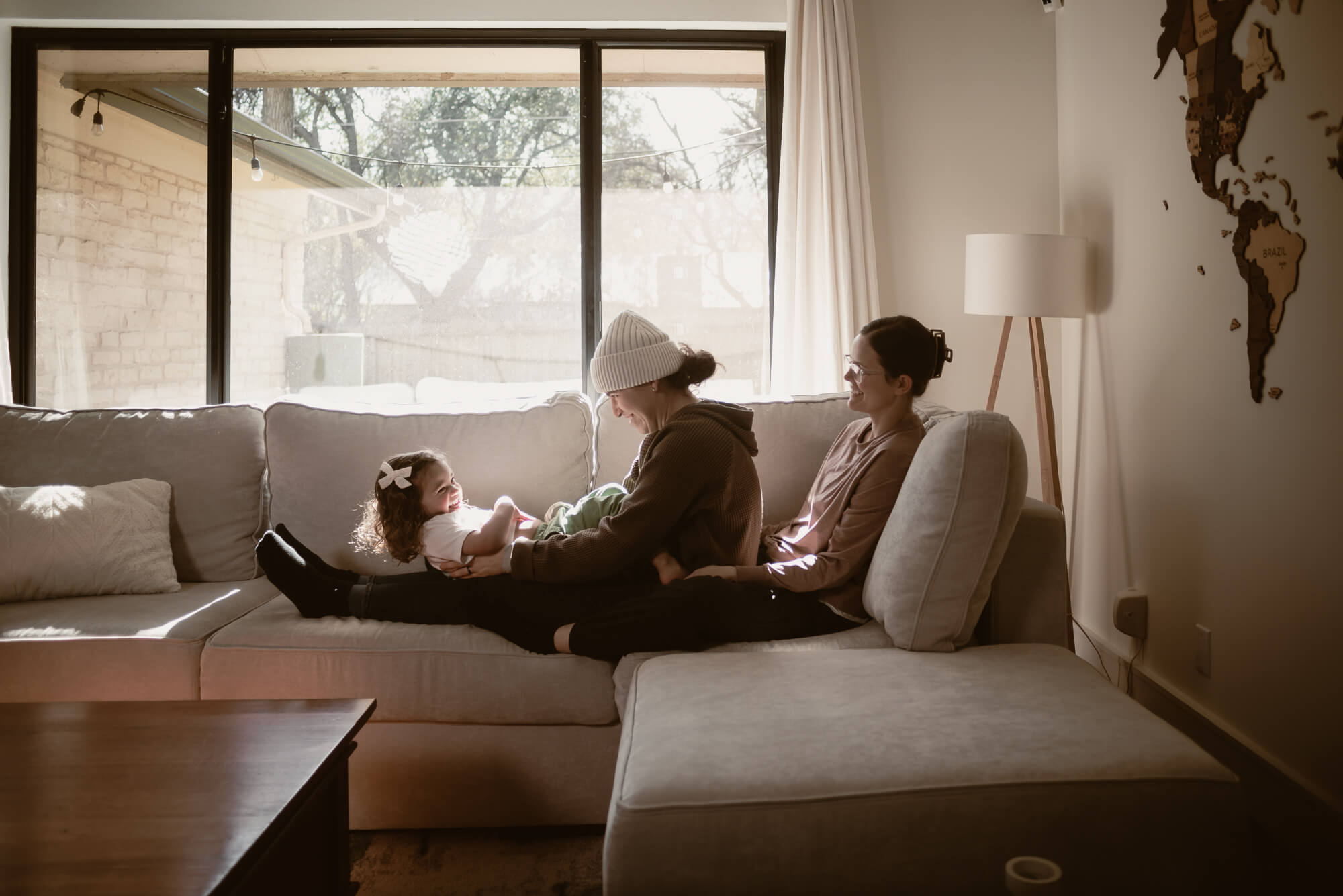 Toddler laughing with their parents inside their home during an in-home family session