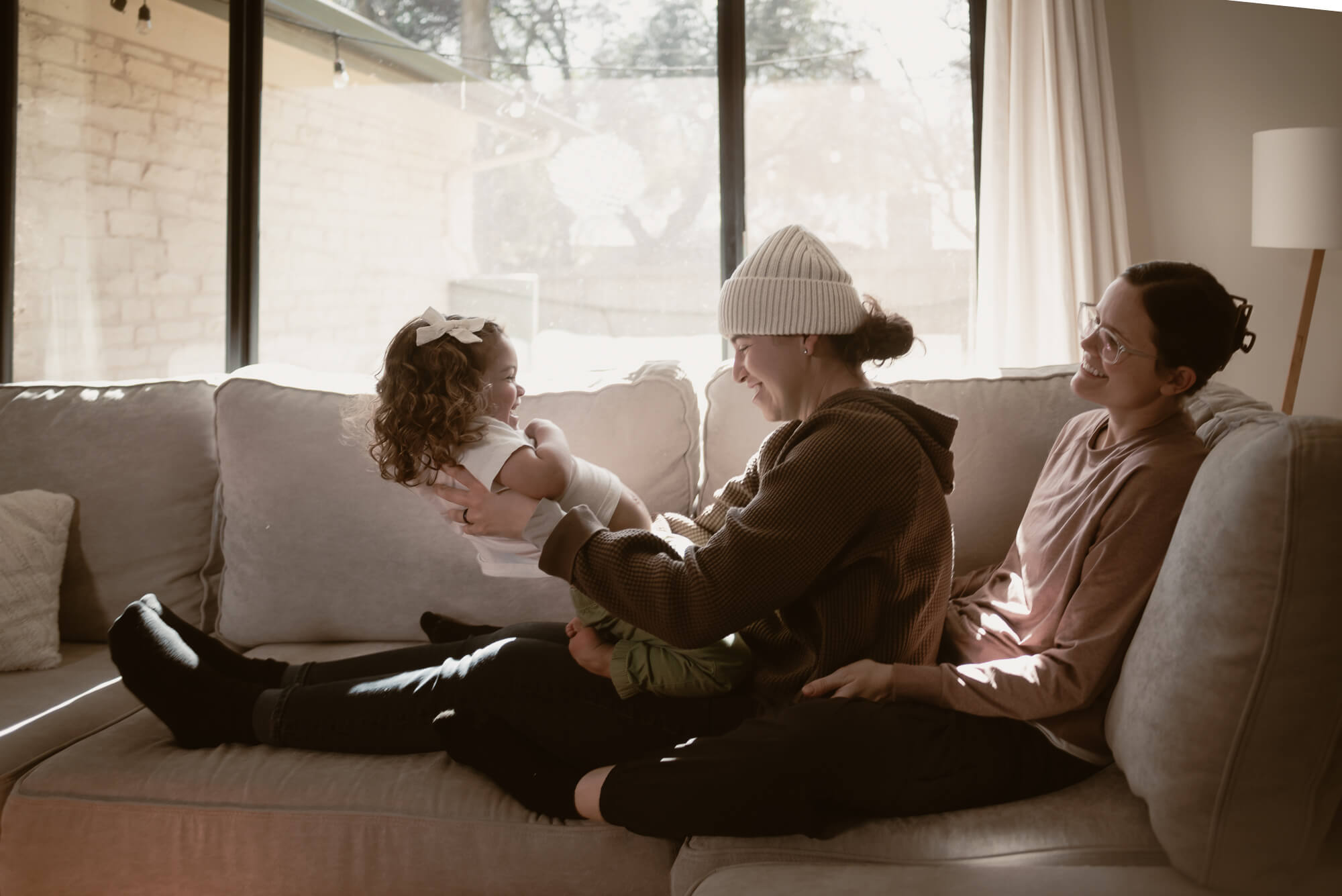 Toddler laughing with their parents inside their home during an in-home family session