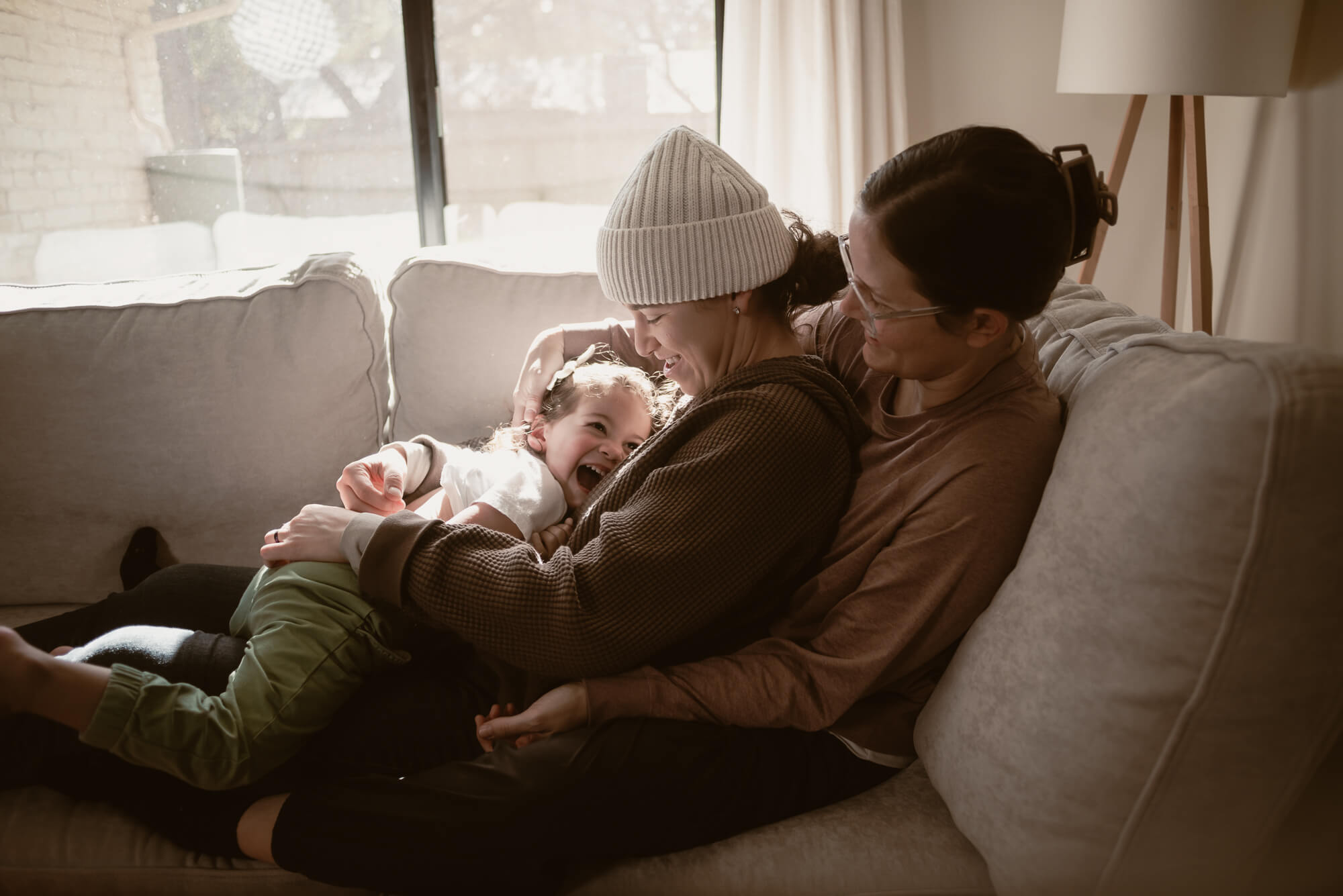 Toddler laughing with their parents inside their home during an in-home family session