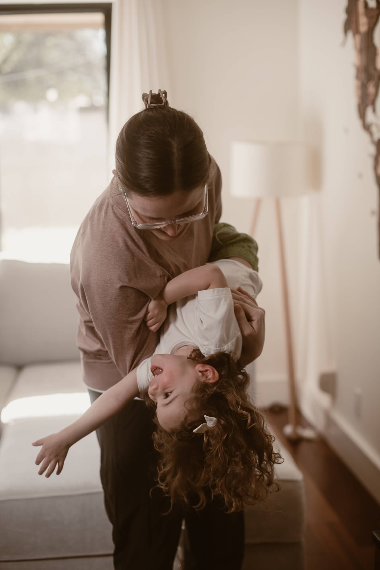 parent holding toddler upside down and playing with her during their indoor family photoshoot in austin texas