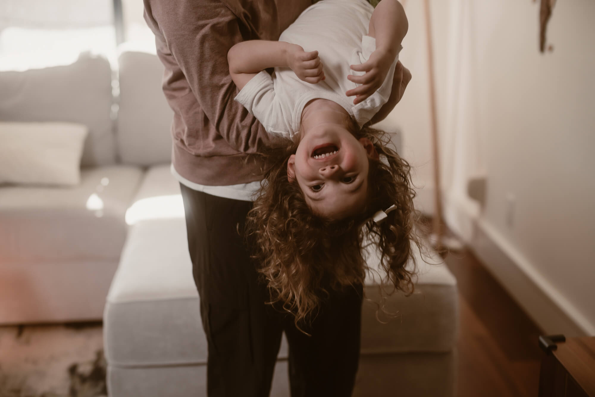 parent holding toddler upside down and playing with her during their family photoshoot in austin texas