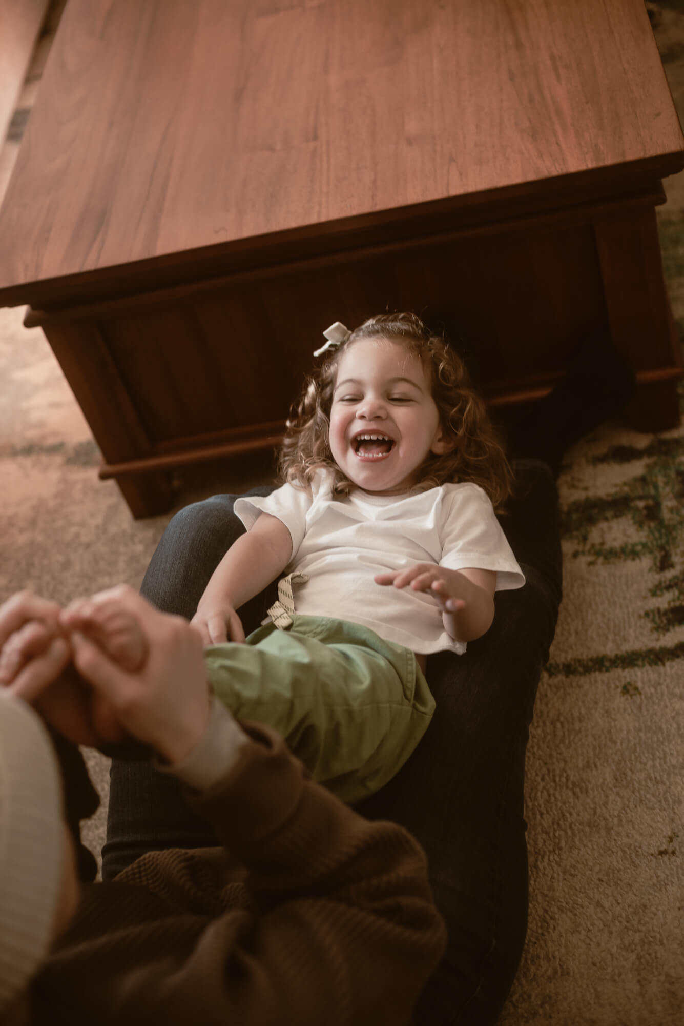 Toddler laughing with their parents inside their home during an in-home family session