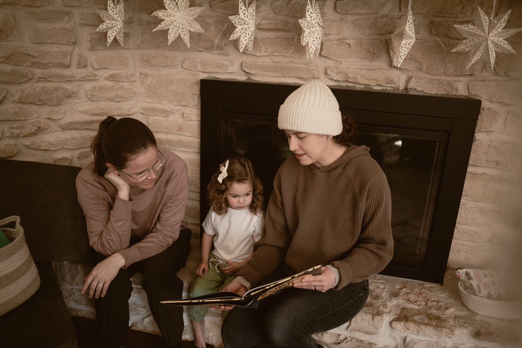 Family reading to their toddler in the living room during their indoor family photoshoot
