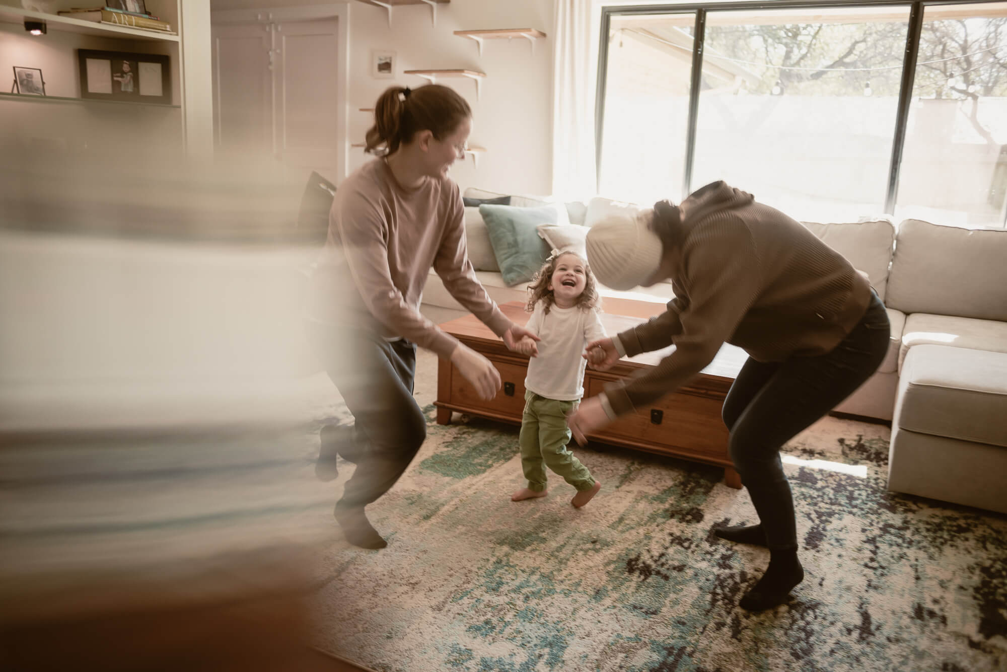 Toddler laughing with their parents inside their home during an in-home family session
