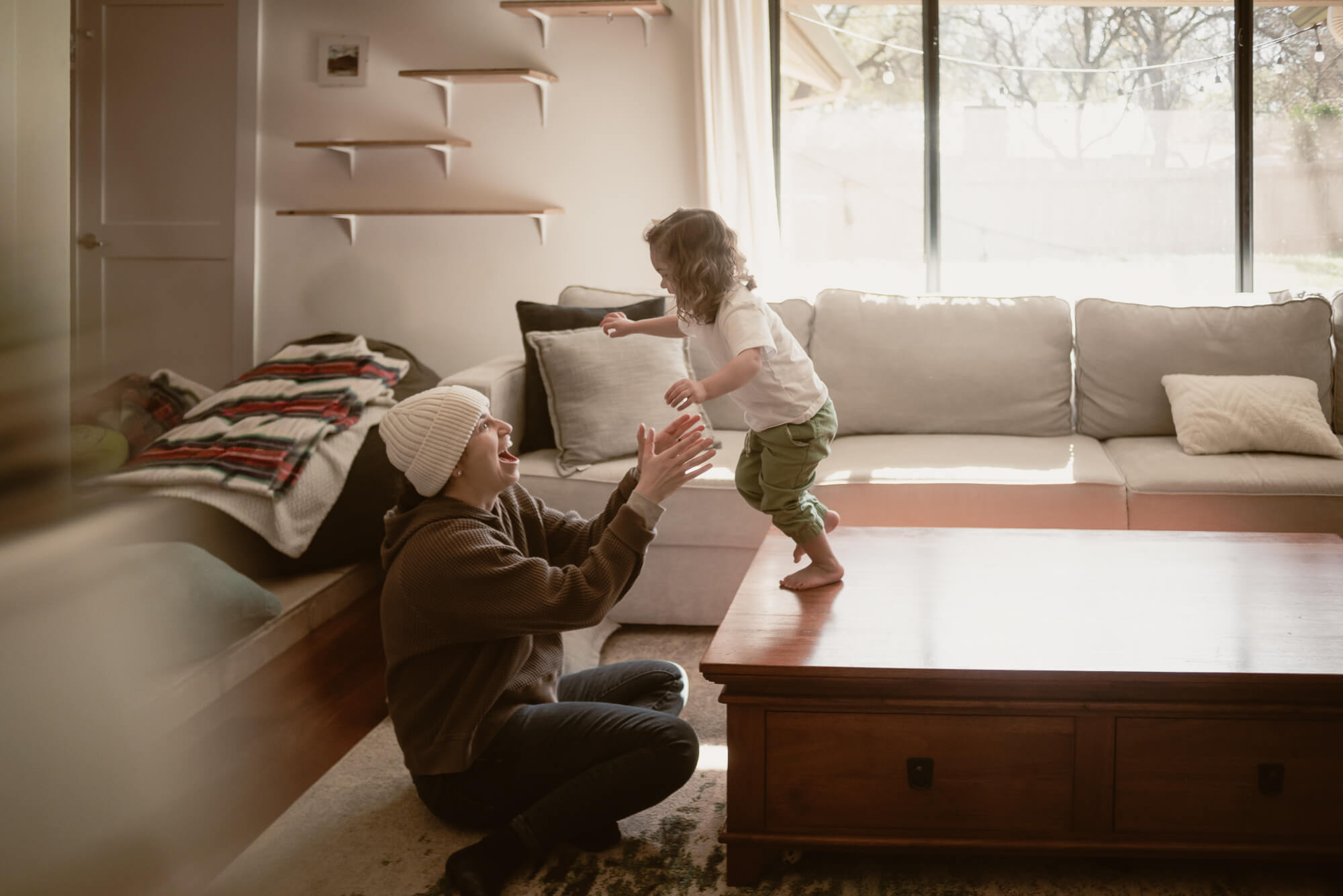 toddler jumping off furniture into her parents arms