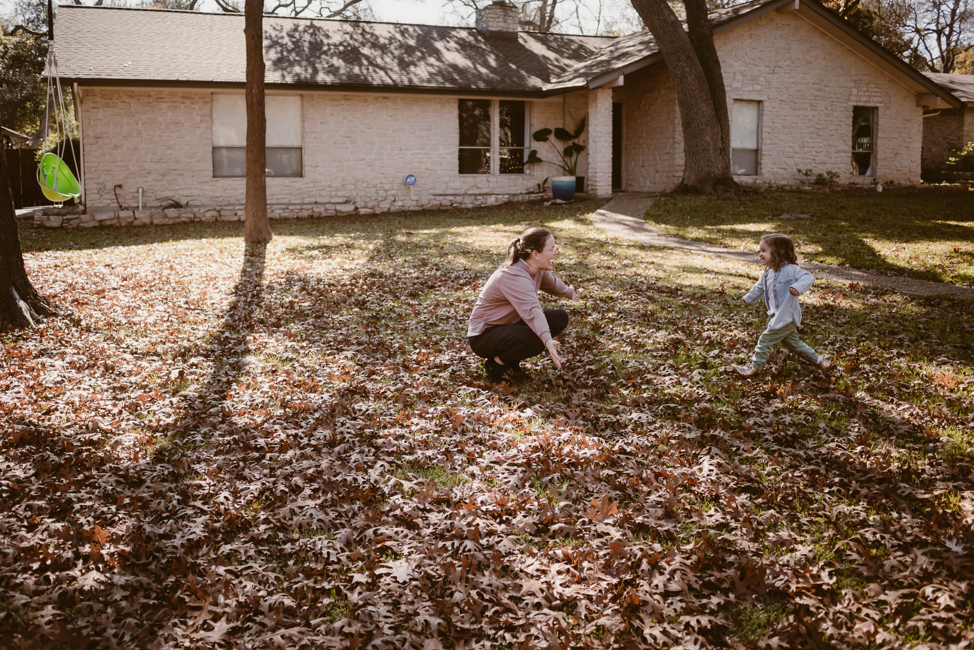 toddler running into her parent's arms during an at home family photoshoot in austin texas