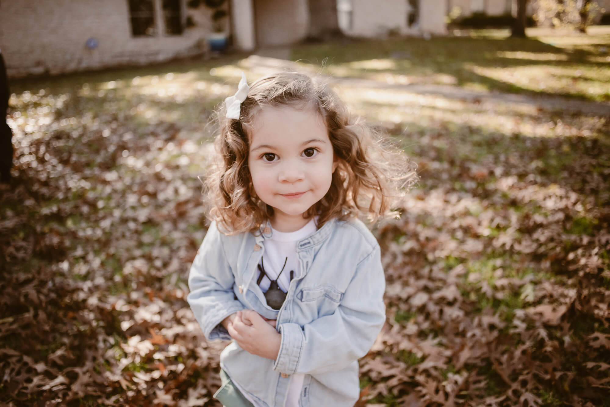 toddler playing outside in the front yard in leaves during an at home family photoshoot in austin texas
