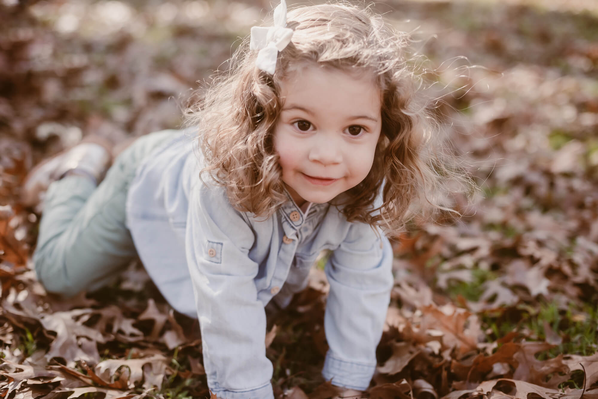 toddler playing outside in the front yard in leaves during an at home family photoshoot in austin texas