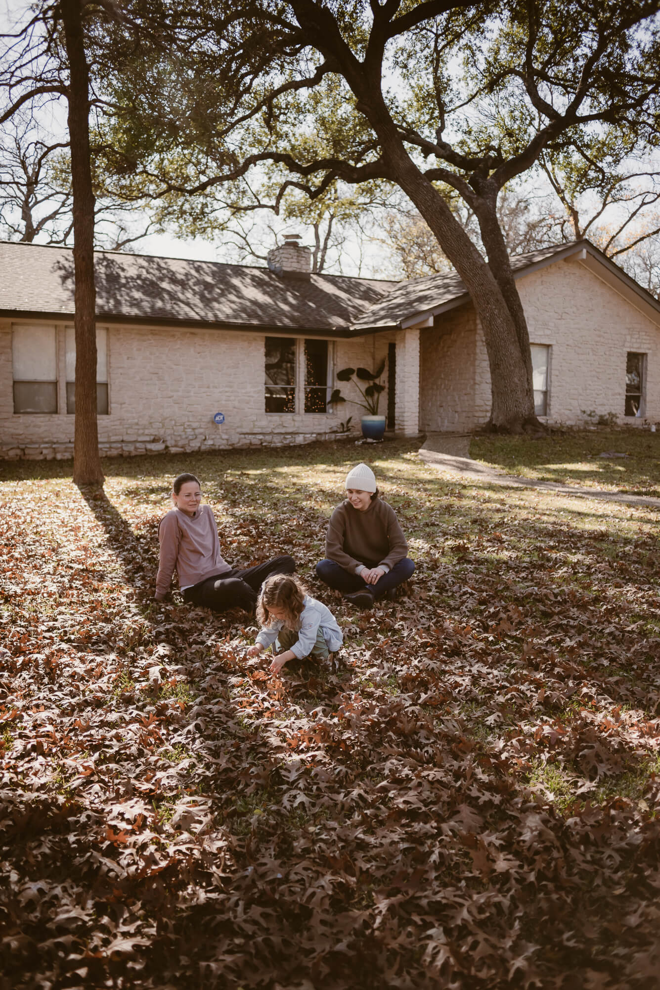 Candid moment of a family laughing in the leaves outside their home in Austin